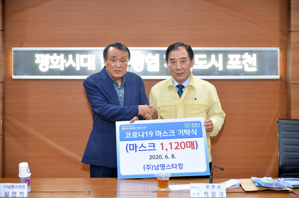 심인학 대표(왼쪽)가 박윤국 시장에게 향균마스크를 전달하고 있다.